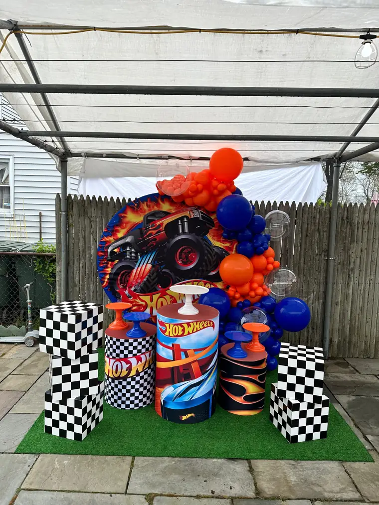 Decoração montada pela Party Decoration Fest no tema Hot Wheels: painel, arco de balões e cilindros com bandejas