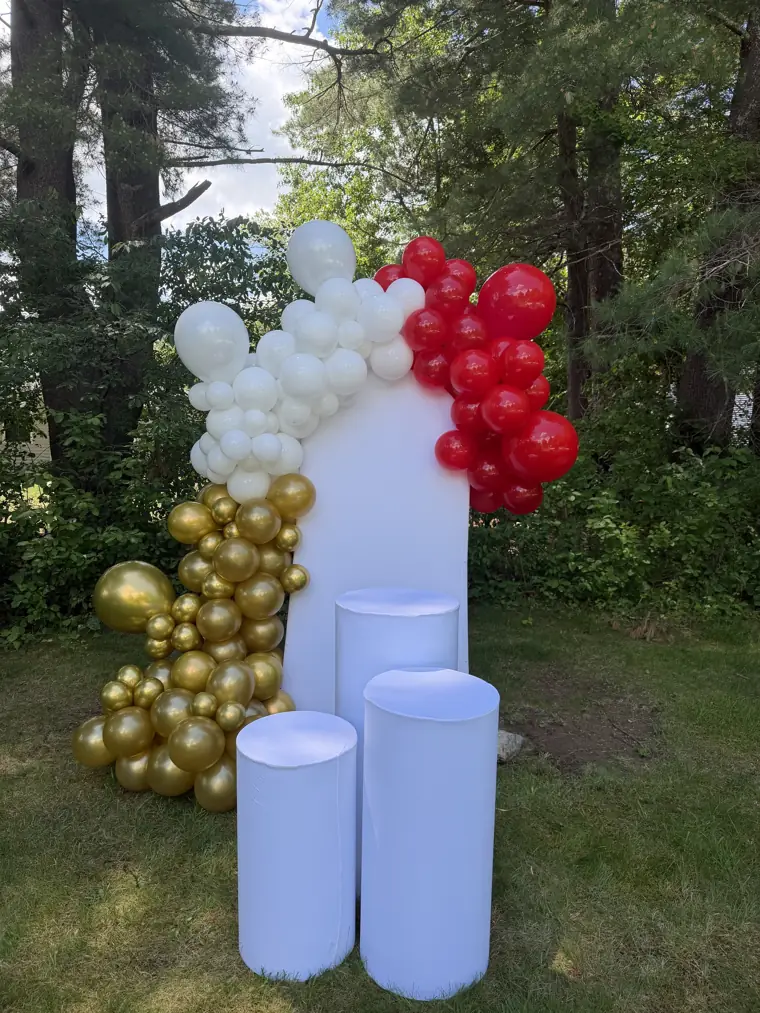 Decoração montada pela Party Decoration Fest no tema Vermelho, branco e dourado: painel, arco de balões e cilindros com bandejas