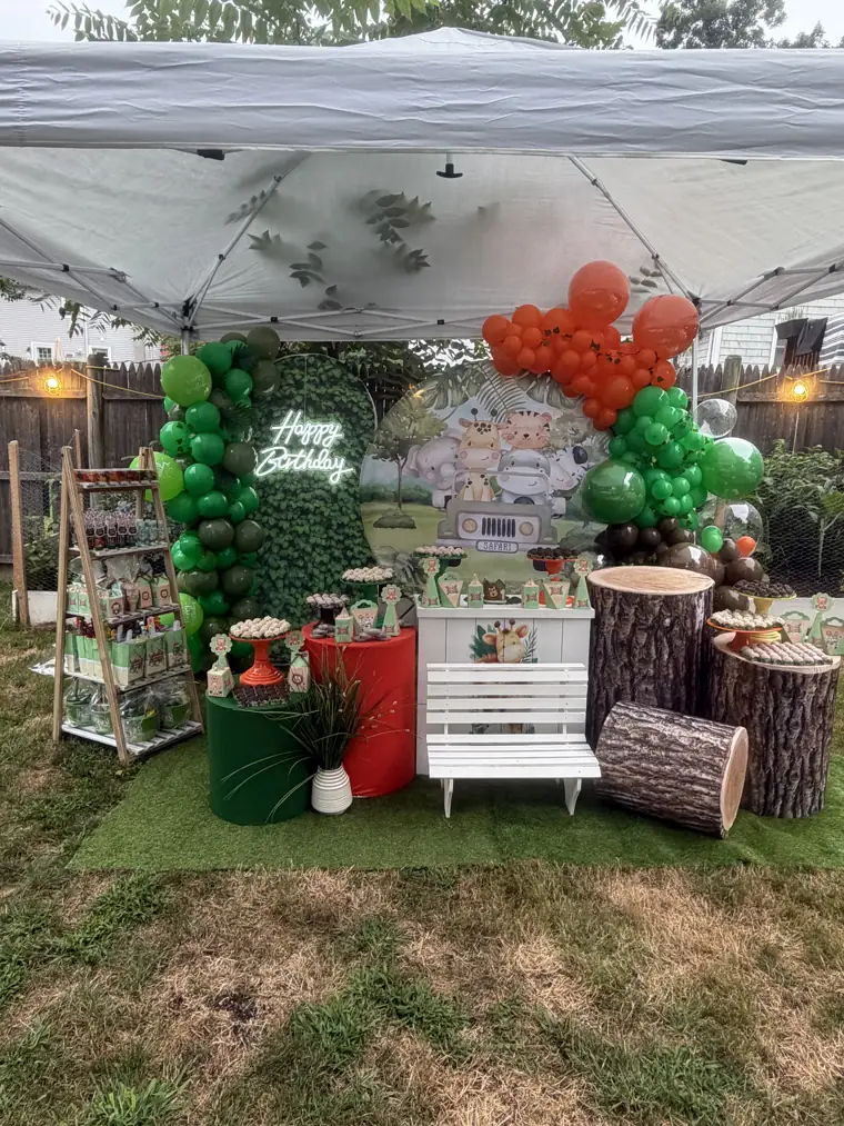 Decoração montada pela Party Decoration Fest no tema Selva: painel, arco de balões e cilindros com bandejas
