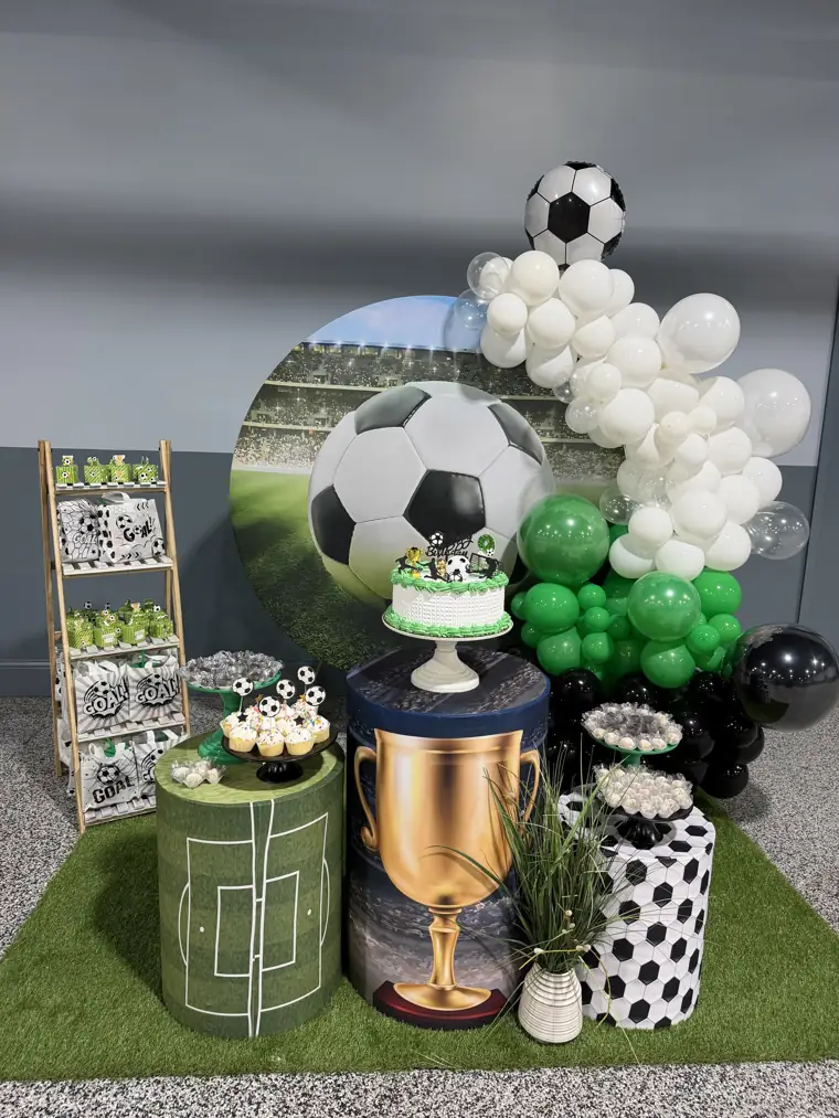 Decoração montada pela Party Decoration Fest no tema Futebol: painel, arco de balões e cilindros com bandejas