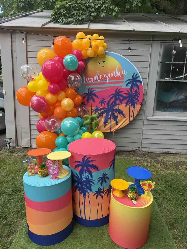 Decoração montada pela Party Decoration Fest no tema Tardezinha tropical: painel, arco de balões e cilindros com bandejas