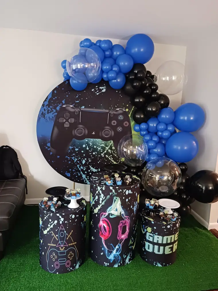 Decoração montada pela Party Decoration Fest no tema Video game: painel, arco de balões e cilindros com bandejas